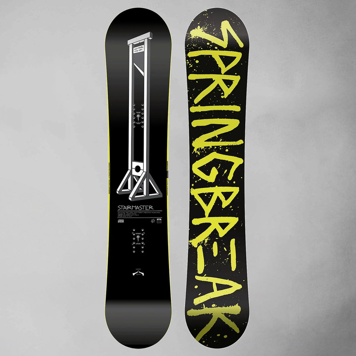 A snowboard shown from both sides against a textured gray background. The base is black with a white graphic on one side and bold yellow 'SNAPBREAK' lettering on the other.