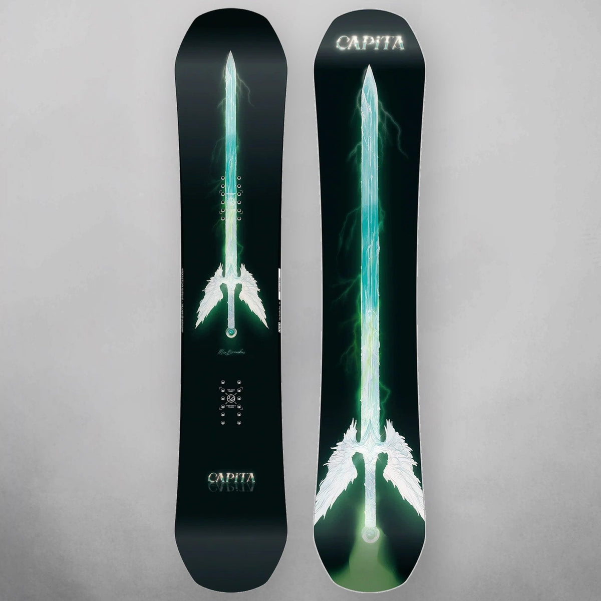 Two CAPiTA snowboards shown vertically against a neutral gray background, featuring a glowing green and white sword graphic on a black base.