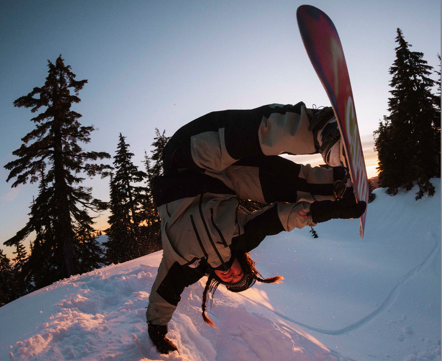 snowboarder doing a hand plant at the top of a half pipe