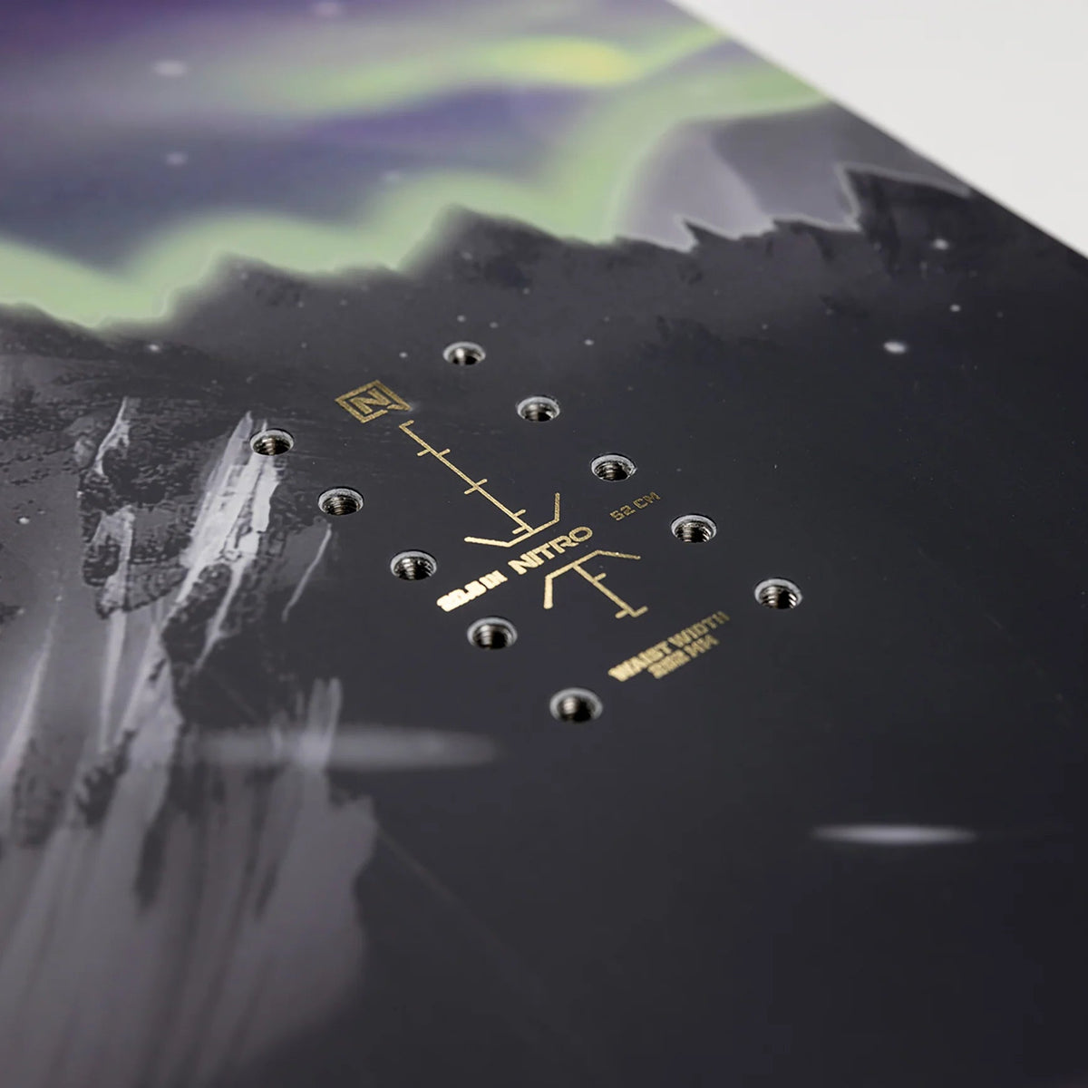 Close-up of a snowboard with a mountain graphic and brand logo on a reflective surface.