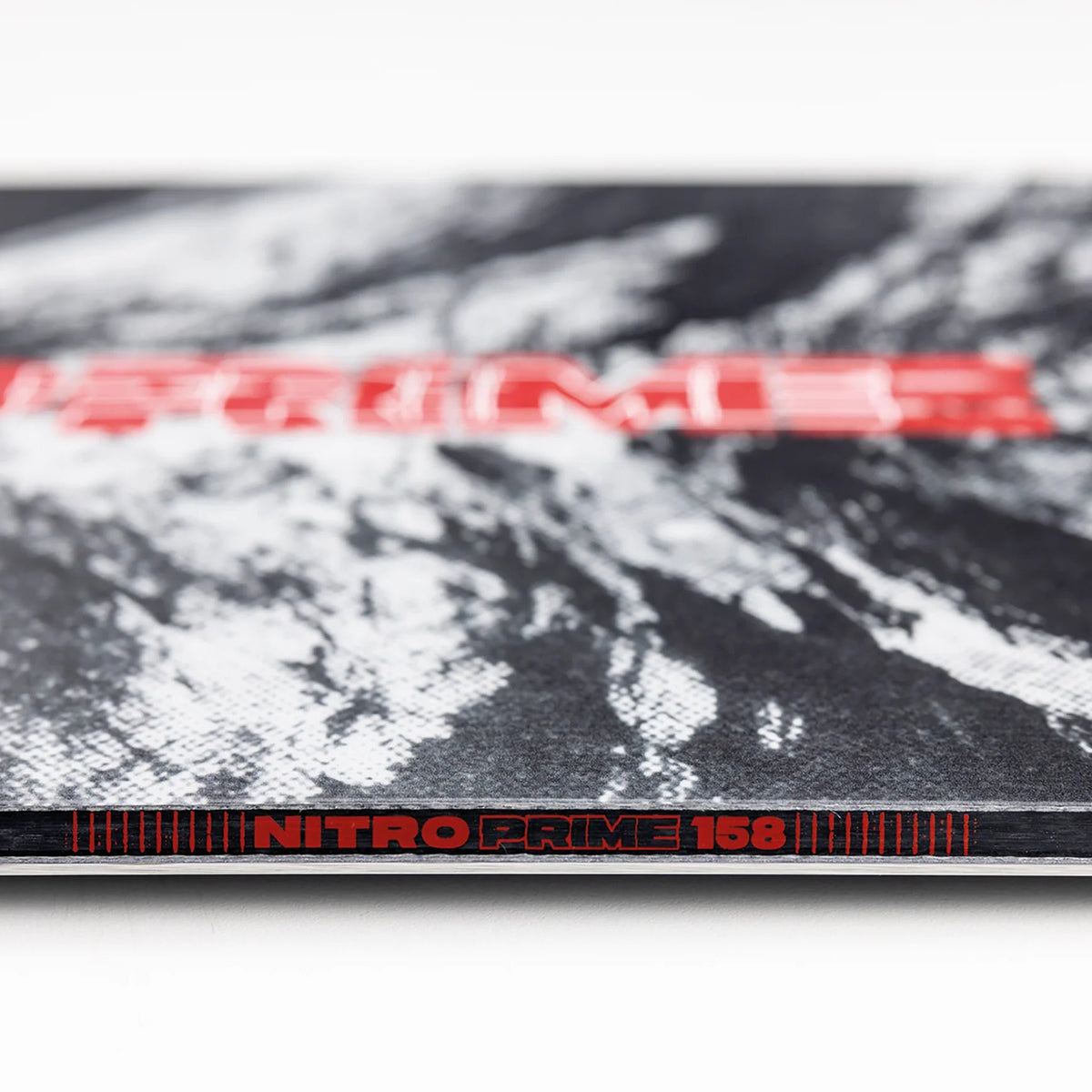 Close-up of a snowboard with 'Prime' and 'Nitro Prime 156' branding on a black and white background.